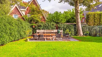 a patio with a table and chairs in a yard at Villa van Reenenpark in Bergen