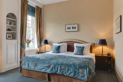 a hotel room with a bed with blue sheets and pillows at Landgoed Duin & Kruidberg in Santpoort-Noord
