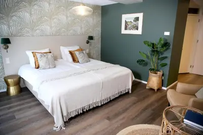 a bedroom with a large white bed and a couch at Landgoed Duin & Kruidberg in Santpoort-Noord