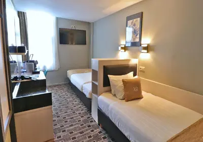 a hotel room with two beds and a desk at XO Hotels City Centre in Amsterdam