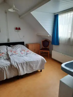 a bedroom with a bed and a chair and a sink at Zomerhuis Visser Egmond in Egmond aan Zee