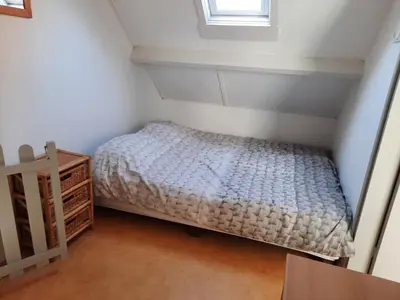 a small bedroom with a bed and a window at Zomerhuis Visser Egmond in Egmond aan Zee