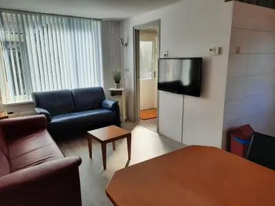 a living room with a couch and a flat screen tv at Zomerhuis Visser Egmond in Egmond aan Zee