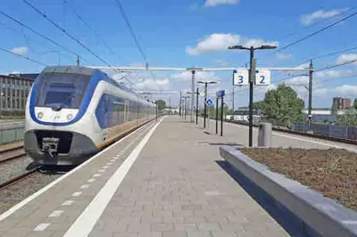 a blue and white train pulling into a train station at Loft met veel zonlicht in Breukelen