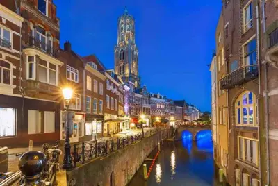 a city at night with a river and a clock tower at Loft met veel zonlicht in Breukelen