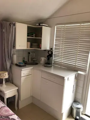 a kitchen with white cabinets and a sink and a window at Romantisch Tiny Gardenhouse in beautiful garden in Zandvoort