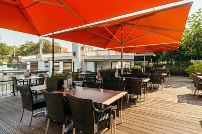 an outdoor patio with tables and chairs and umbrellas at Van der Valk Hotel Leiden in Leiden