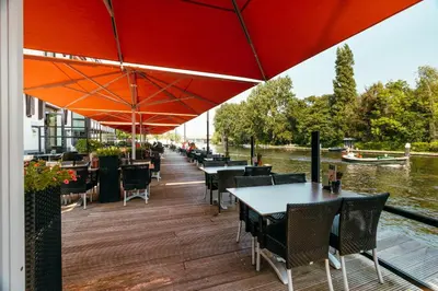 a restaurant with tables and chairs under a red umbrella at Van der Valk Hotel Leiden in Leiden