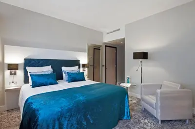 a bedroom with a blue bed and a chair at Van der Valk Hotel Leiden in Leiden