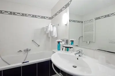 a white bathroom with a sink and a mirror at Van der Valk Hotel Leiden in Leiden