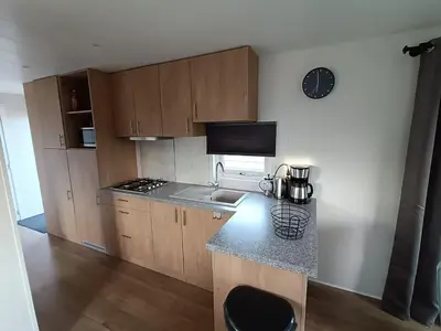a kitchen with wooden cabinets and a counter top at Cozy chalet near Amsterdam at Camping Venhop in Berkhout