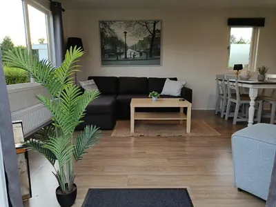 a living room with a black couch and a table at Cozy chalet near Amsterdam at Camping Venhop in Berkhout