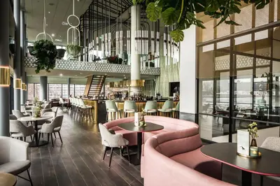 a restaurant with pink chairs and tables and a bar at Van der Valk Hotel Haarlem in Haarlem