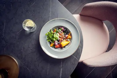 a bowl of salad on a table with a glass of wine at Van der Valk Hotel Haarlem in Haarlem