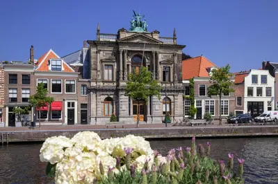an old building next to a river with flowers at Van der Valk Hotel Haarlem in Haarlem