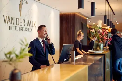 a man talking on a phone at a reception desk at Van der Valk Hotel Breukelen in Breukelen