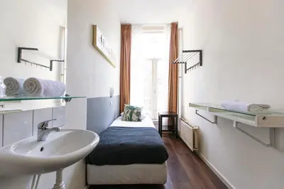 a bathroom with a sink and a bed in it at Quentin Arrive Hotel in Amsterdam