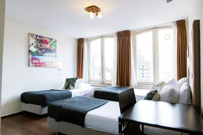 a hotel room with two beds and a table at Quentin Arrive Hotel in Amsterdam