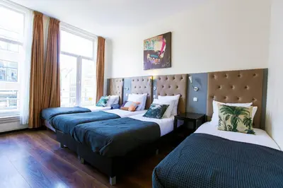 a hotel room with three beds in a room at Quentin Arrive Hotel in Amsterdam