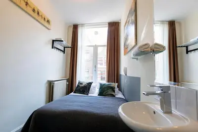 a bedroom with a bed and a sink and a window at Quentin Arrive Hotel in Amsterdam
