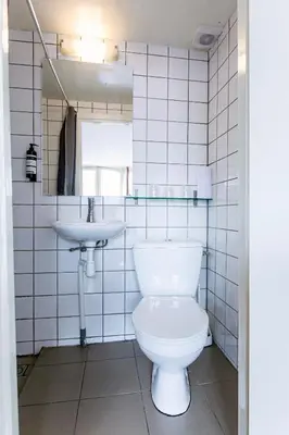 a white bathroom with a toilet and a sink at Quentin Arrive Hotel in Amsterdam