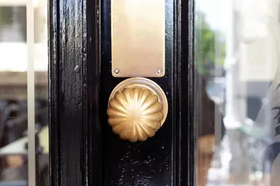 a wooden door with a brass door knocker on it at Quentin Canal House Hotel in Amsterdam