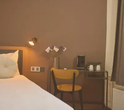 a bedroom with a bed and a desk with a vase of flowers at Quentin Canal House Hotel in Amsterdam
