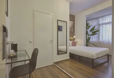 a bedroom with a bed and a desk and a mirror at Quentin Canal House Hotel in Amsterdam