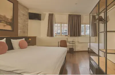 a hotel room with a bed and two windows at Quentin Canal House Hotel in Amsterdam