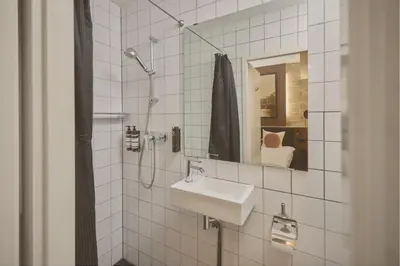 a white tiled bathroom with a sink and a mirror at Quentin Canal House Hotel in Amsterdam