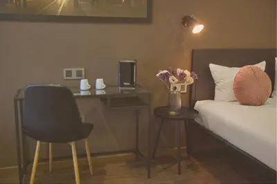 a bedroom with a bed and a desk with a vase of flowers at Quentin Canal House Hotel in Amsterdam