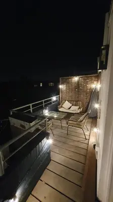 a deck with a table and chairs on a balcony at night at Luminous appartment - Juliana Park free parking in Utrecht