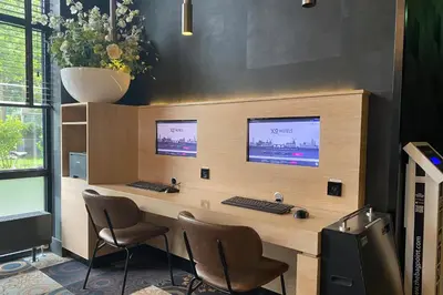 an office with a desk with two monitors and chairs at XO Hotels Couture in Amsterdam