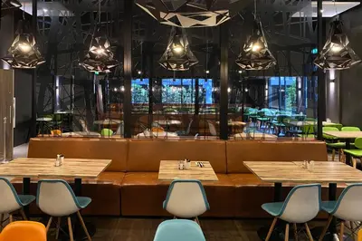 a restaurant with wooden tables and chairs and a large window at XO Hotels Couture in Amsterdam