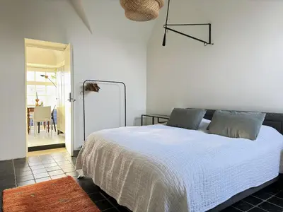 a bedroom with a white bed and a dining room at Apartment in former Bathhouse in Amsterdam