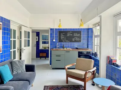 a living room with blue tiled walls and a kitchen at Apartment in former Bathhouse in Amsterdam
