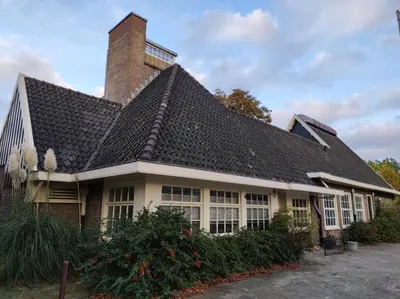 a house with a black roof and a brick chimney at Apartment in former Bathhouse in Amsterdam