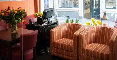 a lobby with two chairs and a desk with a computer at Hotel Continental Amsterdam in Amsterdam