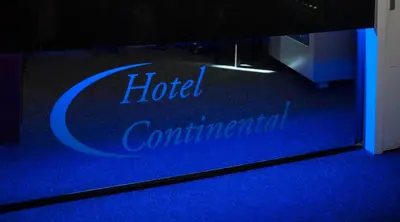 a reflection of a hotel confirmation sign on a blue carpet at Hotel Continental Amsterdam in Amsterdam