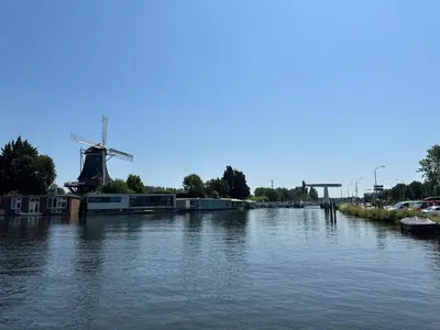 a river with a windmill in the middle of it at Bnb de leeuw in Badhoevedorp