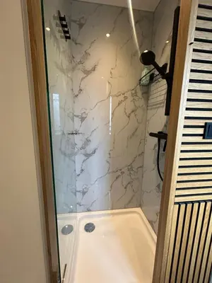a bathroom with a shower with a white marble wall at Bnb de leeuw in Badhoevedorp