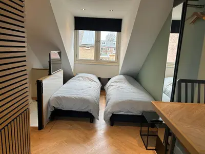 two beds in a small room with a window at Bnb de leeuw in Badhoevedorp