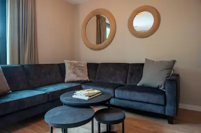 a living room with a blue couch and a table at Parc La Dune Dutch Lodge in Warmenhuizen