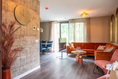 a living room with a couch and a clock on the wall at Parc La Dune Marrakesh Lodge in Warmenhuizen