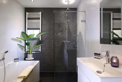 a bathroom with a shower and a tub and a sink at Haarlem Hotel Suites in Haarlem