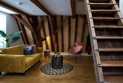 a living room with a yellow couch and a staircase at Haarlem Hotel Suites in Haarlem