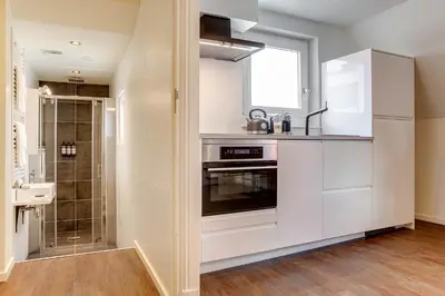 a kitchen with white cabinets and a window at Haarlem Hotel Suites in Haarlem