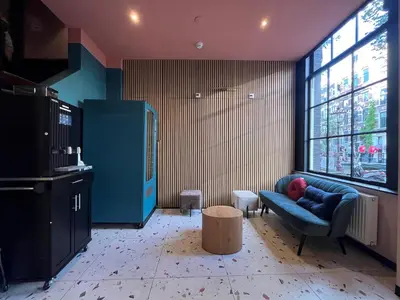 a living room with a blue couch and a window at Heart of Amsterdam Hostel in Amsterdam
