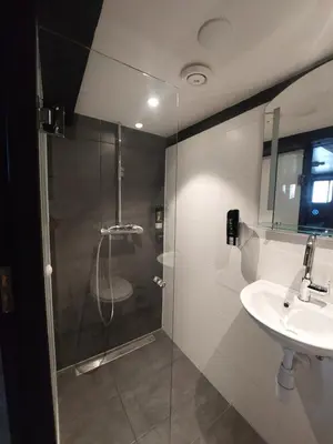 a bathroom with a glass shower and a sink at Heart of Amsterdam Hostel in Amsterdam