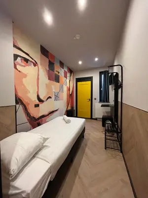 a bedroom with a bed with a painting on the wall at Heart of Amsterdam Hostel in Amsterdam
